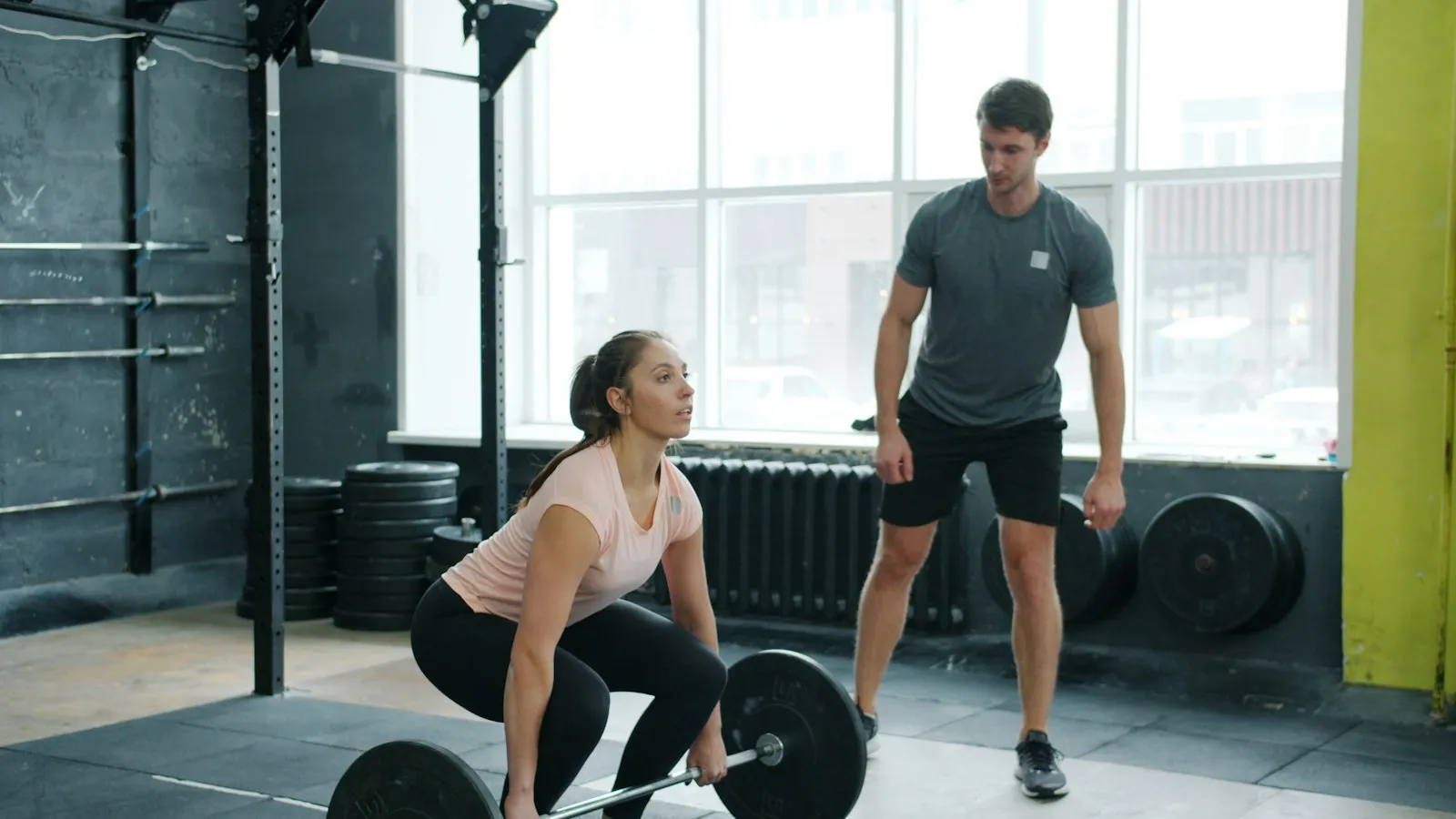 Thomas begeleidt een sporter bij een deadlift in de gym